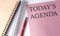 TODAY\'S AGENDA word on the pink paper with office tools on white background