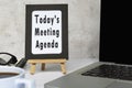 Today's meeting agenda text written on chalkboard with notebook on white desk.