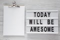 `Today will be awesome` words on modern board, noticepad over white wooden background, overhead view.