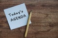 Today's agenda on white notepad with wooden table background. Royalty Free Stock Photo