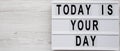 `Today is your day` on a modern board on a white wooden surface, top view. Flat lay, overhead, from above. Copy space