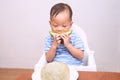 Toddler baby boy child eating melon, Little kid sitting in high chair eating fruit, Self feeding Royalty Free Stock Photo