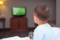 toddler baby boy child sitting in bed holding the tv remote control and watching television Royalty Free Stock Photo