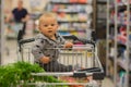 Toddler baby boy, sitting in a shopping cart in grocery store, s Royalty Free Stock Photo