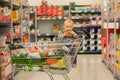 Toddler baby boy, sitting in a shopping cart in grocery store, smiling and eating bread Royalty Free Stock Photo