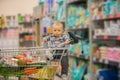 Toddler baby boy, sitting in a shopping cart in grocery store, s Royalty Free Stock Photo