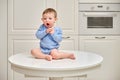 Toddler baby climbed on the kitchen white table. A child in danger clim Royalty Free Stock Photo