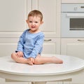 Toddler baby climbed on the kitchen white table. A child in danger clim Royalty Free Stock Photo