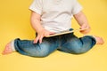 Toddler baby with a digital tablet on a studio yellow background. Happ