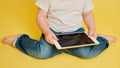 Toddler baby with a digital tablet on a studio yellow background. Happ