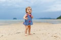 Toddler baby doing her first steps on sand near the bank. Little cute girl playing on the beach. Small child enjoying Royalty Free Stock Photo