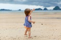 Toddler baby doing her first steps on sand near the bank. Little cute girl playing on the beach. Small child enjoying Royalty Free Stock Photo