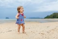 Toddler baby doing her first steps on sand near the bank. Little cute girl playing on the beach. Small child enjoying Royalty Free Stock Photo