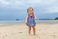 Toddler baby doing her first steps on sand near the bank. Little cute girl playing on the beach. Small child enjoying Royalty Free Stock Photo