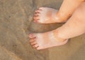 Toddler baby doing his first steps on the beach. Bare feet baby staying on the sand near the bank in sunny day. Summertime holiday Royalty Free Stock Photo