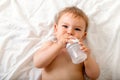 Toddler baby drink water from blue plastic bottle. Sitting on white background. Copy space Royalty Free Stock Photo