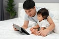 toddler baby with father looking digital tablet pc on bed Royalty Free Stock Photo