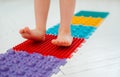 Toddler on baby foot massage mat. Exercises for legs on orthopedic massage carpet. prevention of flat feet and hallux Royalty Free Stock Photo