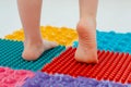 Toddler on baby foot massage mat. Exercises for legs on orthopedic massage carpet. prevention of flat feet and hallux valgus Royalty Free Stock Photo