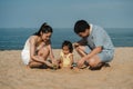 toddler baby girl playing sand toy with father and mother. happy family on the sea beach Royalty Free Stock Photo