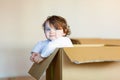 Toddler baby girl sitting inside brown cardboard box. Royalty Free Stock Photo