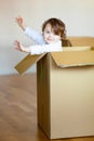 Toddler baby girl sitting inside brown cardboard box. Royalty Free Stock Photo
