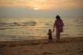 toddler baby girl walking with her mother on sea beach at sunset Royalty Free Stock Photo