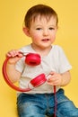 Toddler baby listens to music in red headphones on a studio yellow ba