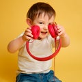 Toddler baby listens to music in red headphones on a studio yellow ba Royalty Free Stock Photo