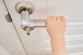 Toddler baby opens the door holding the door handle, child hand close- Royalty Free Stock Photo