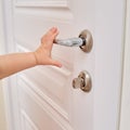 Toddler baby opens the door holding the door handle, child hand close- Royalty Free Stock Photo