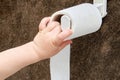 Toddler baby reaches for toilet paper, child s hand with hygiene produc Royalty Free Stock Photo