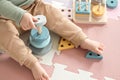 Toddler baby sitting on carpet playing with colorful wooden stacking toy Royalty Free Stock Photo
