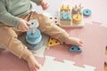 Toddler baby sitting on carpet playing with colorful wooden stacking toy Royalty Free Stock Photo