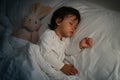 toddler baby sleeping with teddy bear on bed at night Royalty Free Stock Photo