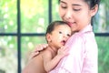 A Toddler baby in tender embrace of mother at the window