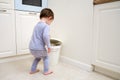 Toddler baby throws garbage in the trash can. A happy child lifts the lid