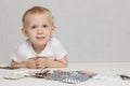 Toddler baby on a white background with pills and medicines