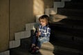 Toddler in blue shirt, jeans, shoes hold stick on staircase