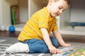 Toddler boy with a bandage or cast on his leg plays with colourful book. Royalty Free Stock Photo