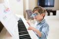 Toddler boy is concentrated on piano and musical notes