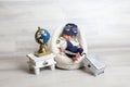 toddler boy in cute pilot costume lying at soft tiny chair little children props travel suitcase globe statue on table Royalty Free Stock Photo