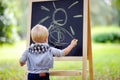 Toddler boy drawing standing by a blackboard Royalty Free Stock Photo