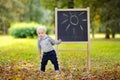 Toddler boy drawing standing by a blackboard Royalty Free Stock Photo