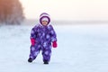 Toddler boy dressing warm winter snowsuit walking on snow field at cold season Royalty Free Stock Photo