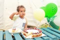 Toddler boy eating cheesecake with fruits and chocolate in front of tent Royalty Free Stock Photo