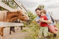 Toddler boy and his father feeding a pony at farm Royalty Free Stock Photo