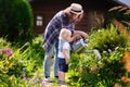 Toddler boy and his young mother watering plants in the garden Royalty Free Stock Photo