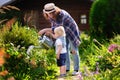 Toddler boy and his young mother watering plants in the garden Royalty Free Stock Photo