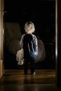 Toddler boy, hodling teddy bear, standing in hallway next to the door to bedroom, fairy tale picture Royalty Free Stock Photo